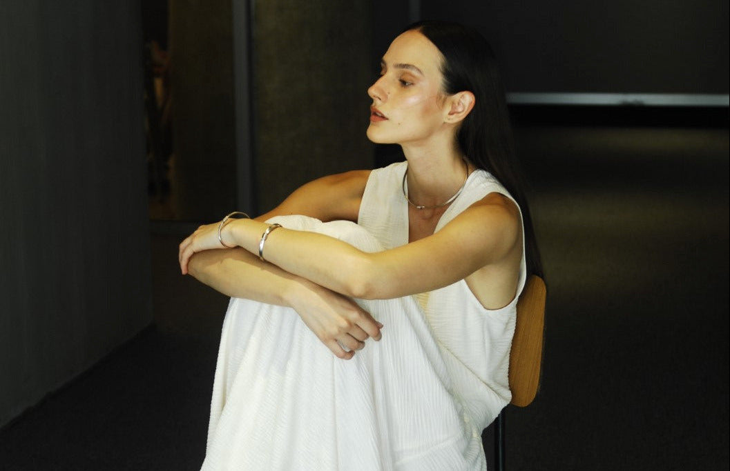 Woman in a white dress sitting on a chair with a dark background