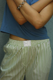 Person wearing a blue shirt and green striped shorts with a visible brand tag.