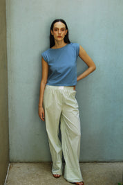 A woman standing wearing green Kyle striped cotton pants with an elasticated waist and side pockets, paired with a Dahlia blue I-shirt.