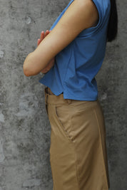 A woman standing wearing a Dahlia blue I-shirt with Camel shorts side