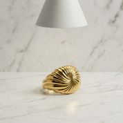 Gold ring on a marble surface with a soft light source