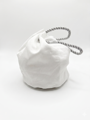 White drawstring bag with a rope handle on a white background