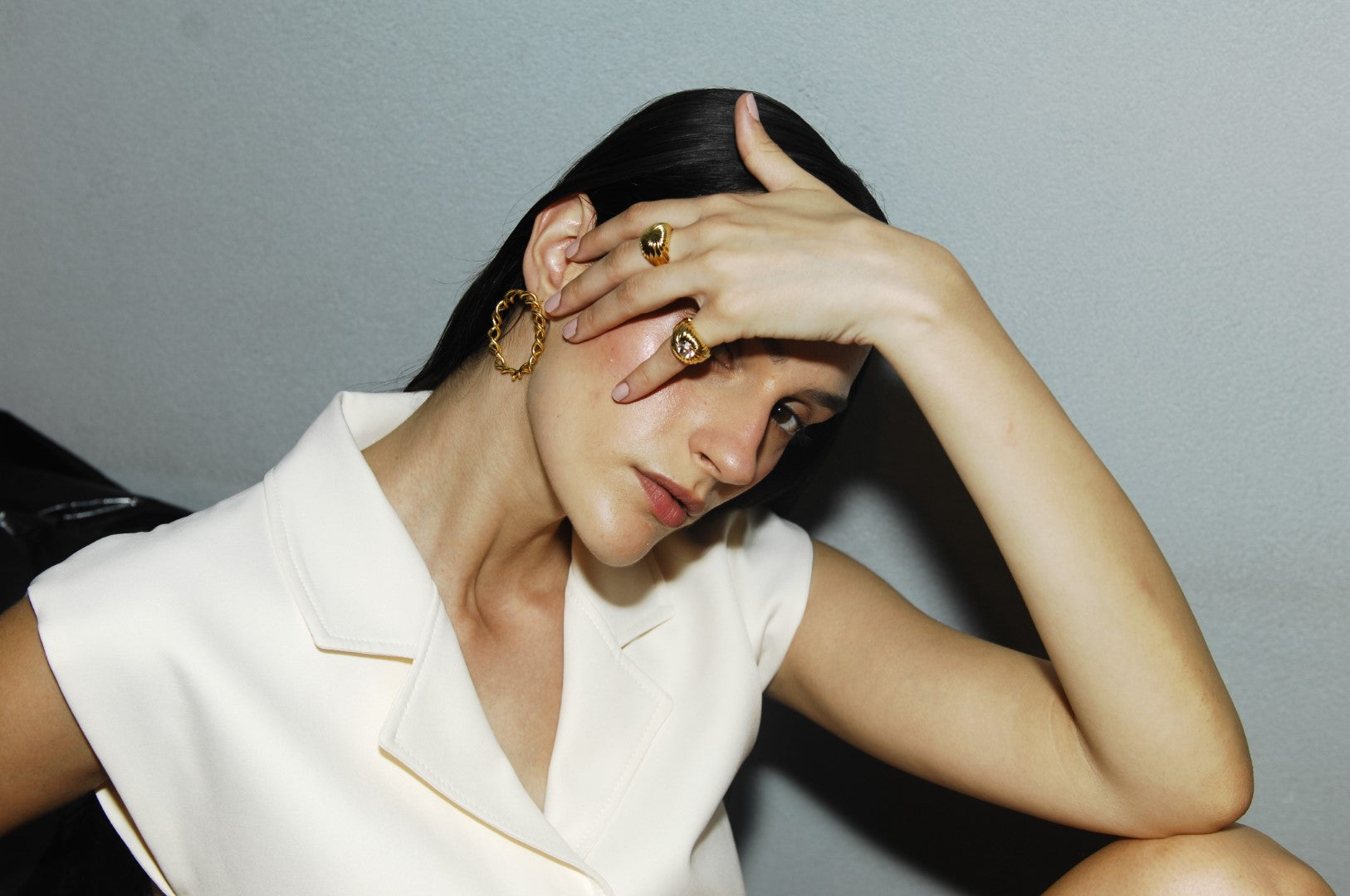 Woman with gold farah signet ring and farah ring posing against a gray background