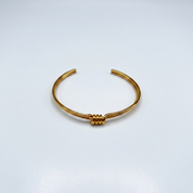 Gold bracelet on a light gray background