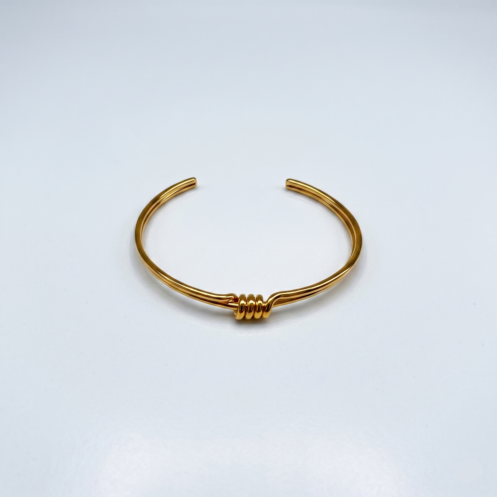 Gold bracelet on a light gray background