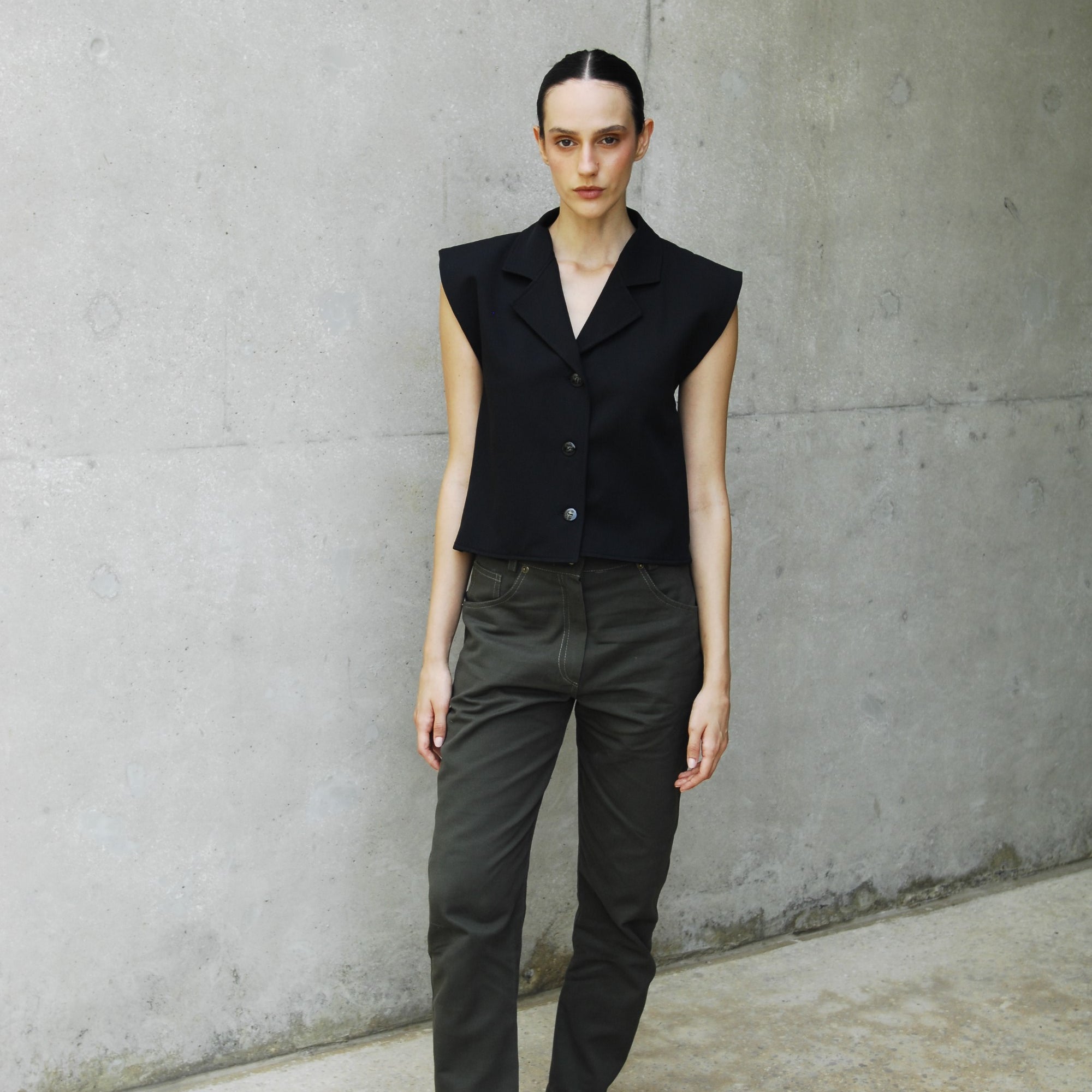 woman wearing a black capri vest standing on a concrete floor.