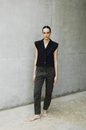 woman wearing a black capri vest standing on a concrete floor.