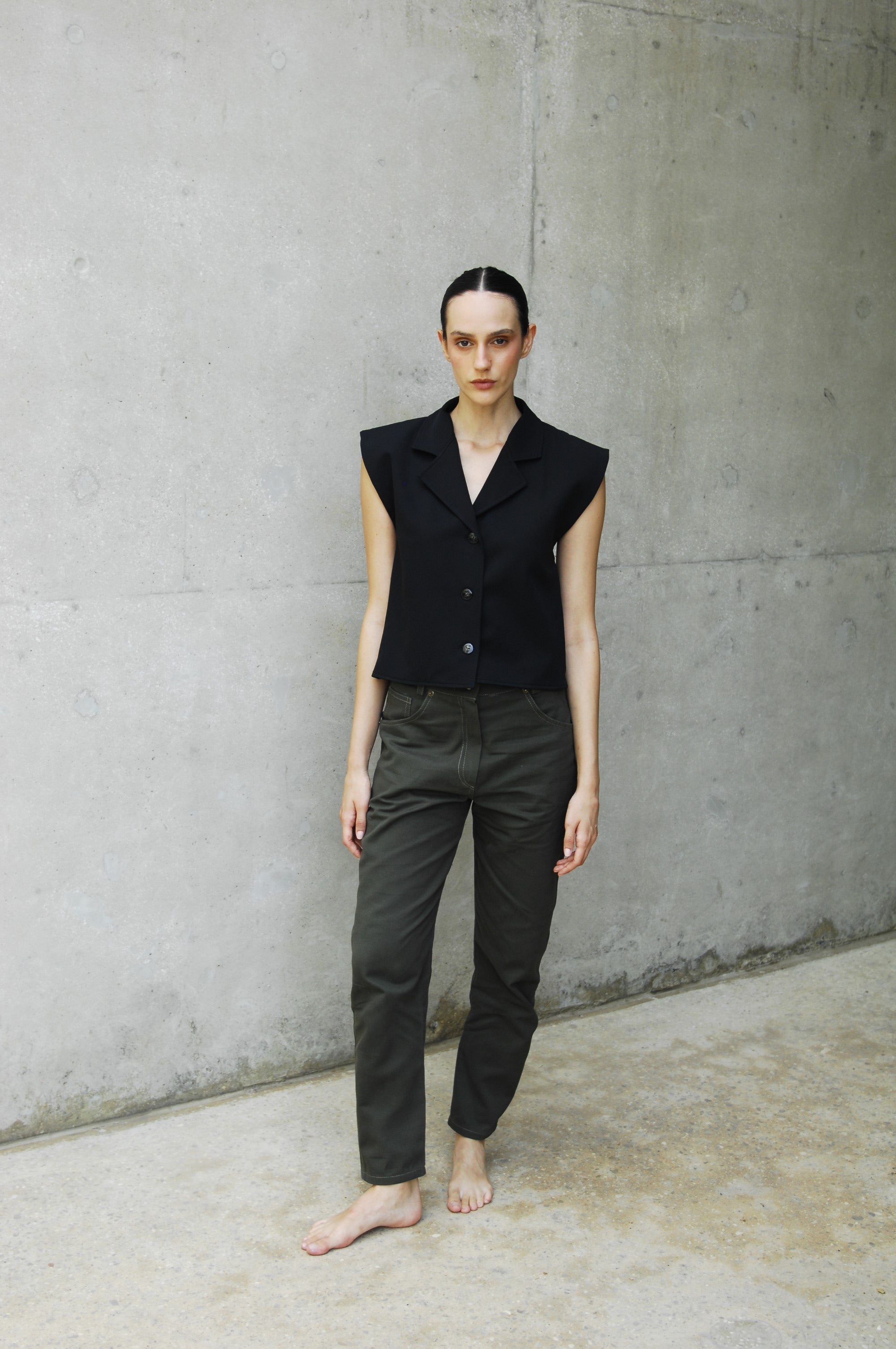 woman wearing a black capri vest standing on a concrete floor.