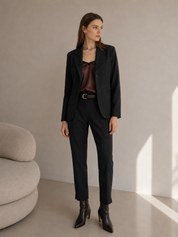 Woman wearing a grey suit with a brown top in a minimalistic room.